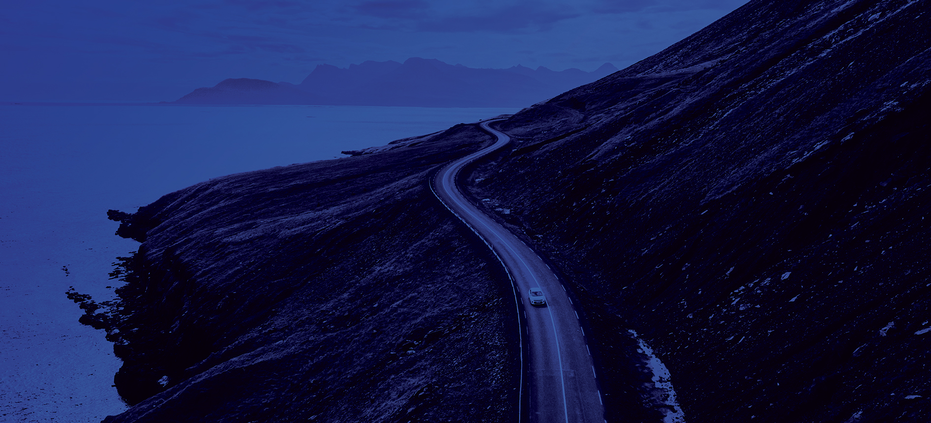 Voiture roulant sur une route côtière.